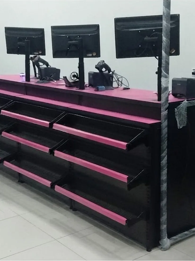 Gôndola central preta com prateleiras e testeiras rosa ao lado do balcão caixa de vidro em loja montada pela ModFix